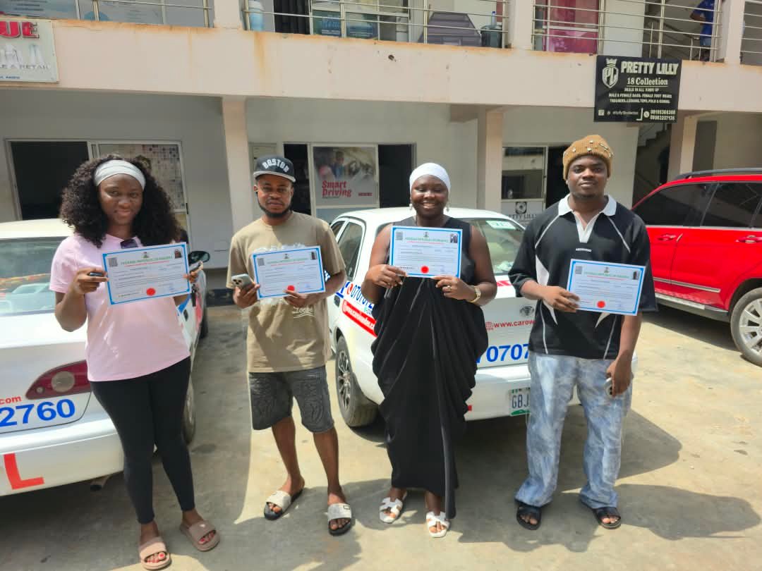 Four CARO Wander graduates holding up their certificates in front of CARO training cars